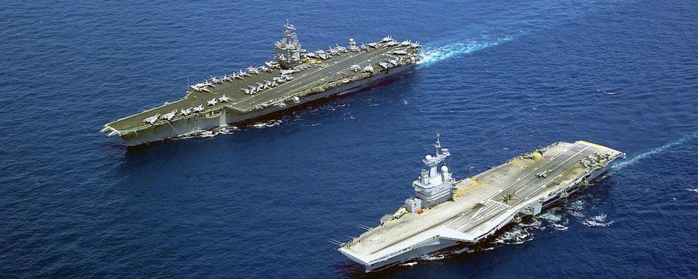 Charles de Gaulle i förgrunden bredvid USS Enterprise från USA. Foto: US Navy/Wikimedia Commons