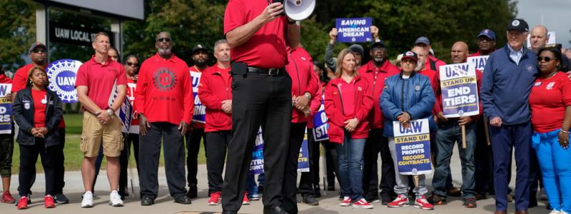 Evan Vucci/AP/TT: UAW:s ordförande Shawn Fain leder strejkprotester, med bland andra president Joe Biden som åhörare.