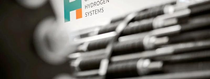 Green Hydrogen Systems' logotyp bakom elektrolysörstackar som är ur fokus. Foto: Green Hydrogen Systems.