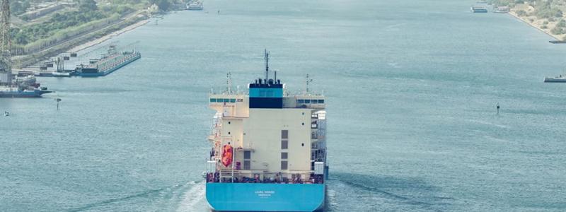 Ett stort containerfartyg med Maersks färger vid ingången till Suezkanalen, vars stränder omges här av grön vegetation. Foto: Maersk