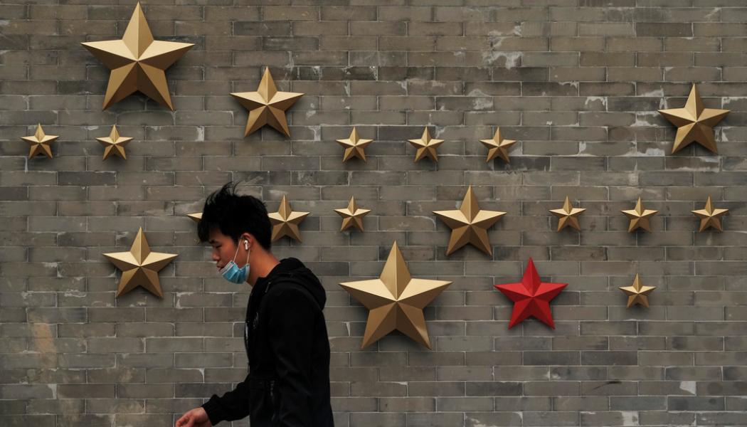 Andy Wong/AP/TT: En invånare i Peking passerar kommunistpartiets symbol utanför en restaurang. Arkivbild.